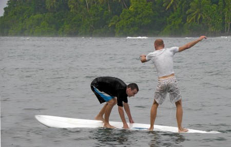 Two fools trying to stand on a sailboard